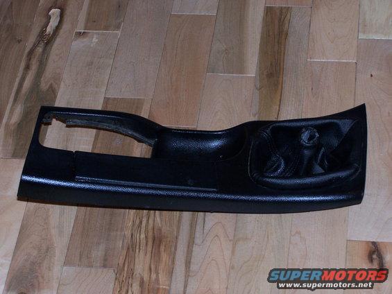 Black car door panel with handle cutout, resting on a wooden floor