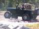 1989 Ford Bronco - A black Jeep Wrangler navigates an off-road course with large tires and a roll cage visible.
