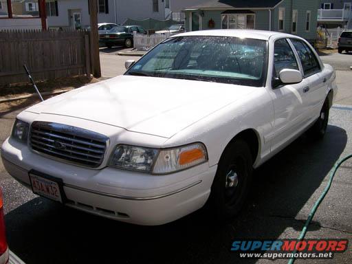 White sedan with a chrome grille and black wheels, viewed from the front three-quarter angle