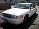 1999 Ford Crown Victoria - A white sedan, possibly a Ford Crown Victoria, is parked outdoors on a sunny day.