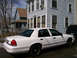 1999 Ford Crown Victoria - Side view of a white Ford Crown Victoria sedan parked on a street.
