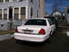 1999 Ford Crown Victoria - A white Ford Crown Victoria is parked in a driveway next to a dark SUV.