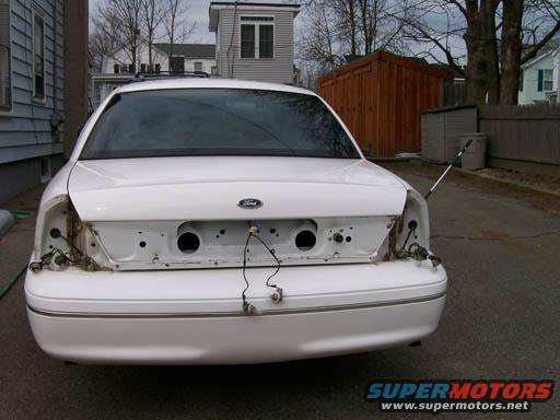 White Ford Crown Victoria, rear bumper and taillights removed, showing wiring and internal structure. License plate area is empty
