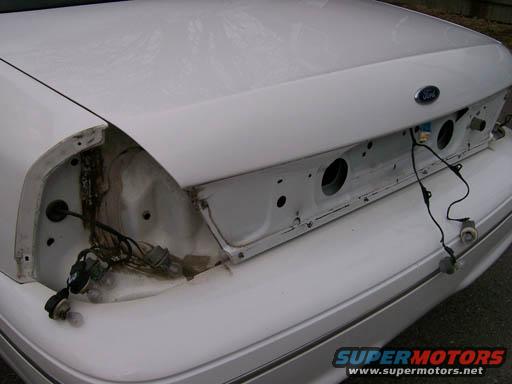 Rear of a white Ford Crown Victoria with taillights removed, showing wiring and trunk area