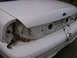 1999 Ford Crown Victoria - The rear of a white Ford Crown Victoria is shown with its taillights removed, exposing the internal wiring and trunk compartment.