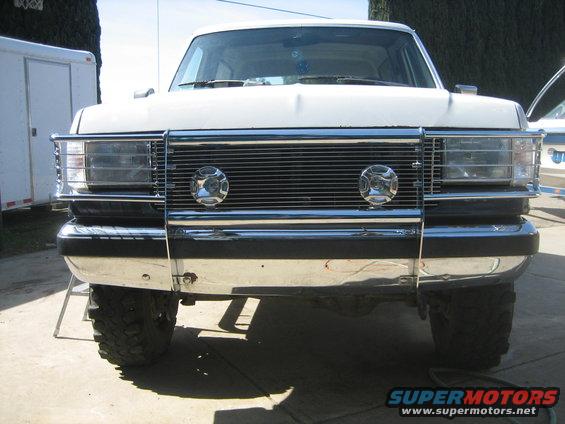White Ford Bronco front view, chrome grille with two round lights, chrome bumper, large tires