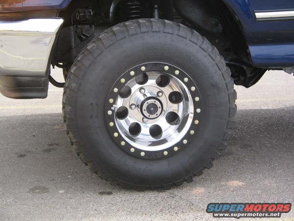 Close-up of a large off-road tire with a chrome beadlock wheel on a blue SUV