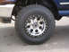 1995 Ford Bronco - A close-up view of a modified wheel and tire assembly on a blue SUV.