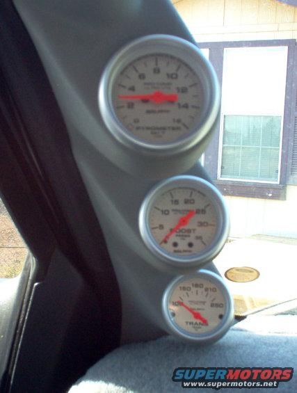 Interior view of three gauges mounted on a gray pillar; one reads PYROMETER, another BOOST, and the bottom reads TRANS