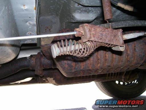 Underbody view of rusty exhaust system and brake cable