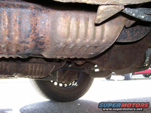 underbody of a rusty vehicle, showing exhaust and suspension components