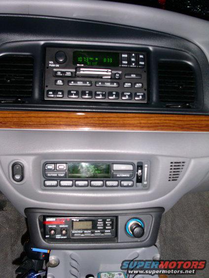 Car dashboard with three radios stacked, wood trim, and air vents