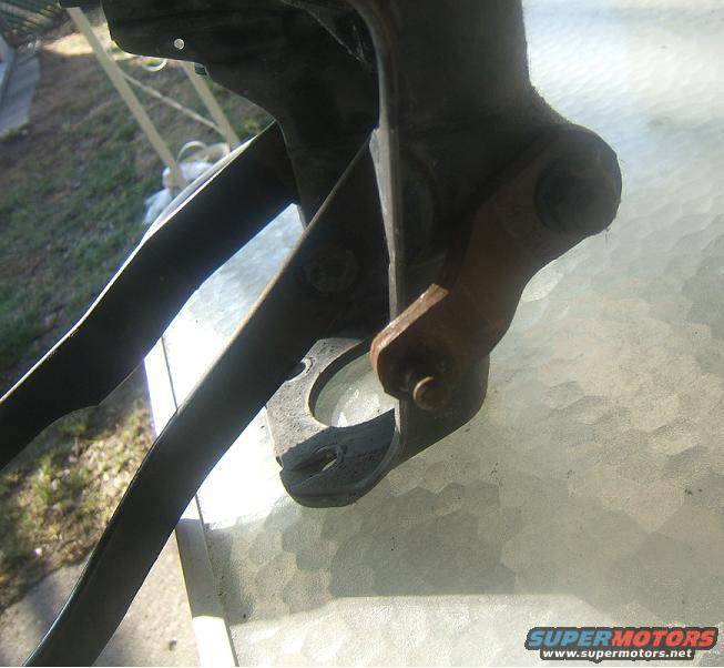 Close-up of a rusty metal bracket with bolts, resting on a glass table