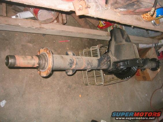 Rear axle assembly with differential housing and brake drum flange. Rusty metal components are visible