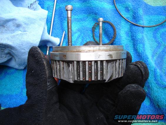 Gloved hand holding a damaged metal manual hub with two bolts inserted