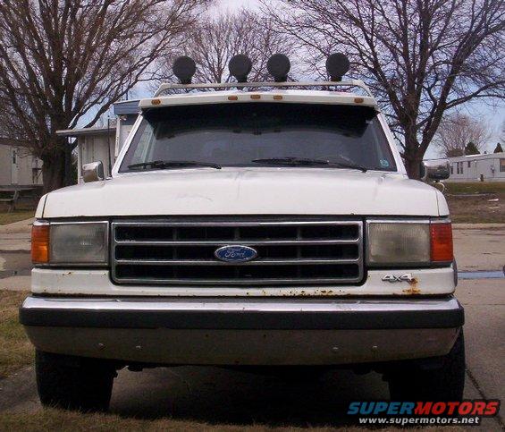 White Ford F-Series truck front view, has roof lights and 4x4 badge
