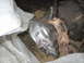 1994 Ford Bronco - A close-up view of a rusty bracket on a vehicle's transfer case component, partially covered by plastic.