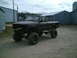 2001 Dodge 2500 - A dark, heavily modified pickup truck with oversized tires sits in a dirt lot, its front grille removed.