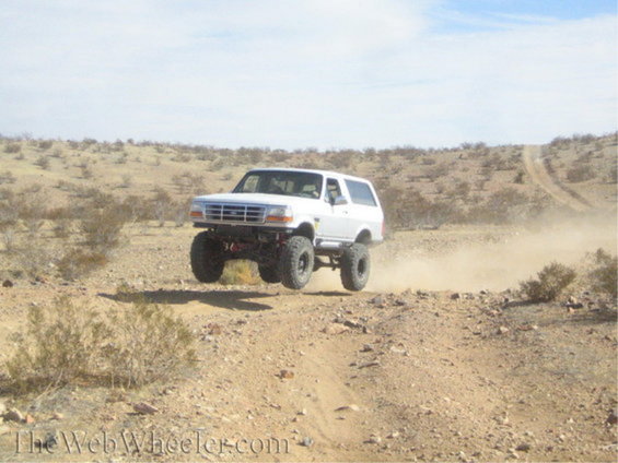 White 1996 Ford Bronco mid-air over a desert trail
