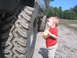 1990 Ford Bronco - A young child stands next to the enormous tires of a lifted vehicle.