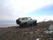 1996 Ford Bronco - A silver 1996 Ford Bronco is parked on a dirt hill under a cloudy sky, with a spare tire mounted on the rear.