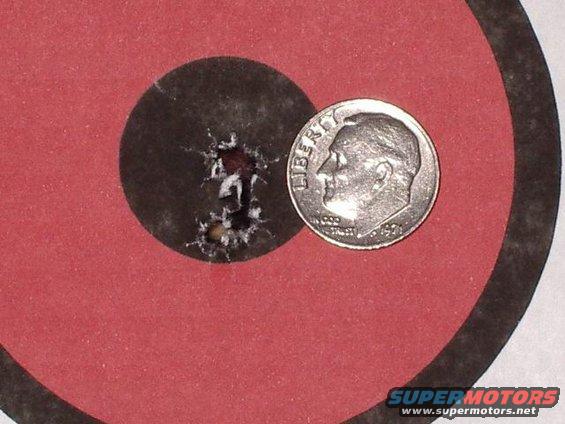 Target with bullet holes next to a dime for scale