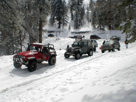 Red Jeep Wrangler with roll cage in snow