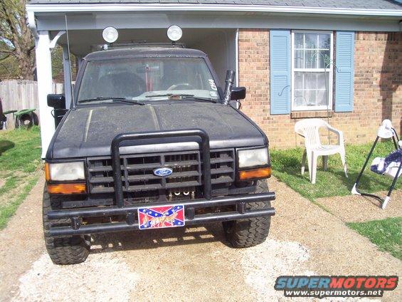 Front view of a dusty black 1989 Ford Bronco II with a bull bar and two lights on the roof
