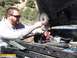 1986 Ford Bronco - Man uses a grinder on a car engine while working outdoors.