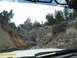 1986 Ford Bronco - Two off-road vehicles navigate a challenging rocky trail through a dry, wooded landscape, as seen from the perspective of another vehicle.