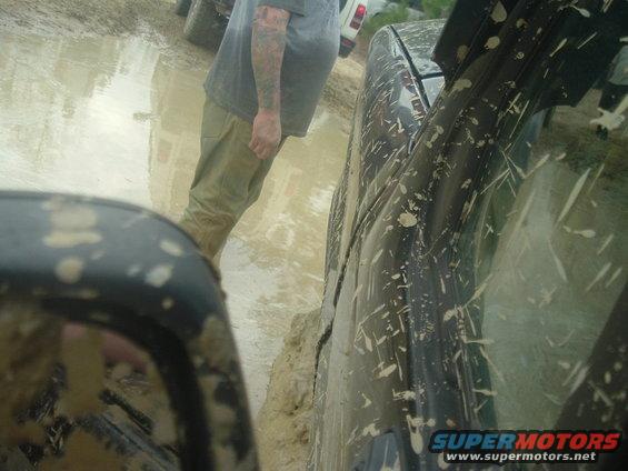 Two trucks stuck in deep mud, one is black and covered in mud splatters