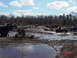 1995 Dodge 1500 - Multiple trucks and ATVs navigate a muddy off-road course under a partly cloudy sky. The scene is dominated by mud and water features.