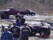 1995 Dodge 1500 - Two pickup trucks and an ATV are in a muddy field with several people observing.