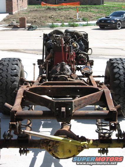 Vehicle chassis and engine with large tires; black car in background