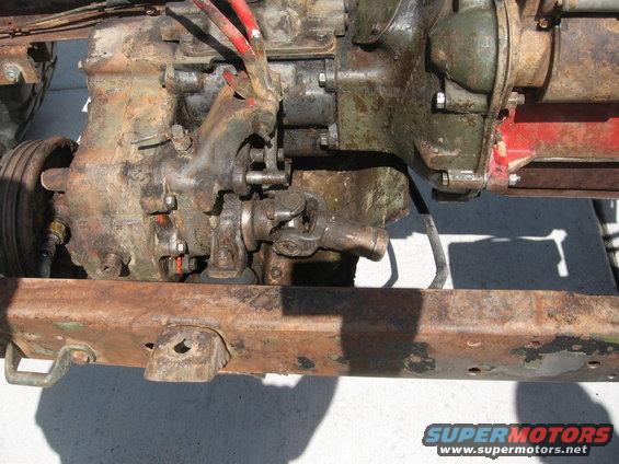 Close-up of a rusty drivetrain component with red hoses attached