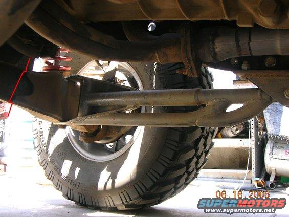 Underside view of a vehicle's suspension and exhaust system, showing a large tire