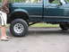 1974 Ford F-100 - Side view of a green pickup truck with aftermarket wheels and tires, indicating a lifted suspension.