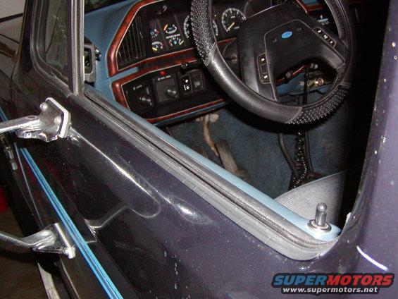 Dark blue interior of a 1987 Ford Bronco showing dashboard, steering wheel, and door frame