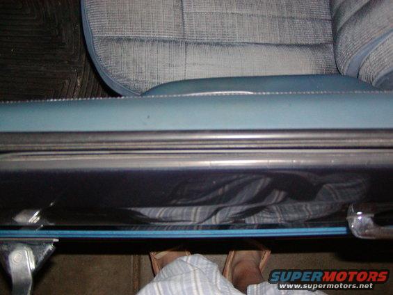 Close-up of a car's interior door sill and part of the seat. A person's feet are visible below the sill