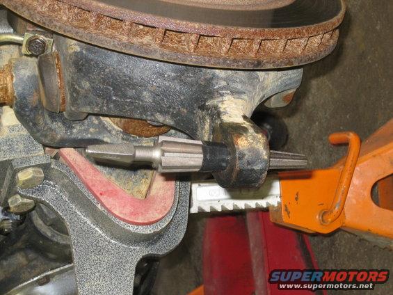 Close-up of a vehicle's steering linkage with a splined tool inserted