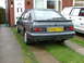 1988 Ford Sport - The Ford Sierra hatchback is parked on a driveway in front of a house, with a white van to its right.