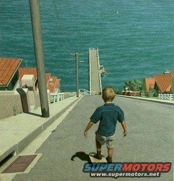 Boy on skateboard on steep street with houses and ocean view