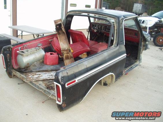 Black Ford F-Series truck cab and bed with red interior, air compressor, and gas cans in the bed