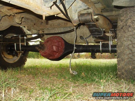 Underside of a vehicle showing the rear axle, leaf springs, and part of a tire