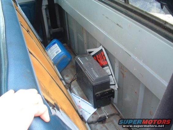Interior of a truck bed with a blue jug, Sony device, and "FOR SALE" signs