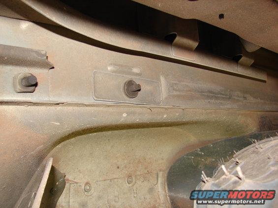 Underside of a vehicle showing frame rails and part of a tire