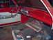 1963 Ford Ranchero - The interior of a red 1963 Ford Ranchero, viewed from the passenger side, reveals its dashboard and door panel details.