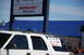 1996 Ford Bronco - A white SUV is parked in front of a building with a blue roof and a Mercury sign.