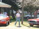 1966 Ford Ranchero - Two red cars are parked outside with a woman standing in the middle.