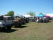 1978 Ford Bronco - A gathering of Ford trucks and a Bronco under tents on a sunny day.